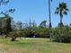 Tennis court surrounded by green grass and shady trees on a sunny day at 4260 Placida Rd # 21C, Englewood, FL 34224