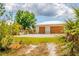 A wide two-car garage has a white roof, brown doors, and is surrounded by lush landscaping and some open area at 5250 Callaway St, Port Charlotte, FL 33981