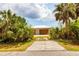 A long driveway leads up to the large garage with a white roof that is surrounded by tropical plants at 5250 Callaway St, Port Charlotte, FL 33981