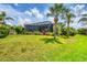 Lush backyard featuring a large screened lanai and mature palm trees at 585 Coral Creek Dr, Placida, FL 33946