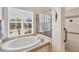 Large soaking tub next to shower with safety handles and window with plantation blinds at 585 Coral Creek Dr, Placida, FL 33946