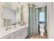 Bathroom featuring a white vanity, sink, and toilet, accented by unique wallpaper and neutral tile flooring at 5879 Venisota Rd, Venice, FL 34293