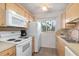 Functional kitchen with white appliances, light wood cabinetry, and a window for natural light at 708 Tamiami S Trl # 216, Venice, FL 34285