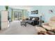 Bright living room with a black sofa, comfy chairs, sliding doors to a balcony, and neutral-colored carpet at 708 Tamiami S Trl # 216, Venice, FL 34285