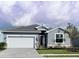 Charming single-Gathering home featuring a grey tile roof, brick-paved driveway, and lush landscaping at 8244 Shore Lake Dr, Englewood, FL 34224