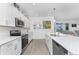 Open kitchen featuring white cabinetry, stainless steel appliances, and bar seating at 8244 Shore Lake Dr, Englewood, FL 34224
