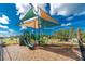 Community playground with sunshade cover, slide, and climbing features surrounded by wood mulch and green space at 8244 Shore Lake Dr, Englewood, FL 34224