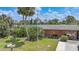 Lush backyard with a light-colored single-story home with light latticework details and tropical landscaping at 857 Palmetto St, Englewood, FL 34223
