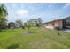 Expansive backyard featuring a light-colored single-story home with tropical landscaping and a small shed at 857 Palmetto St, Englewood, FL 34223