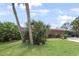 Lush backyard with a light-colored single-story home with light latticework details and tropical landscaping at 857 Palmetto St, Englewood, FL 34223