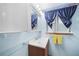 Cozy bathroom featuring a wood vanity, blue walls, and matching blue curtains with yellow towels at 857 Palmetto St, Englewood, FL 34223