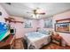 Comfortable bedroom featuring pink walls, a patterned comforter, shelves, and natural light from the windows at 857 Palmetto St, Englewood, FL 34223