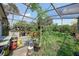 Enclosed patio featuring a greenhouse and an array of potted plants under a screened roof at 857 Palmetto St, Englewood, FL 34223