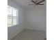 Bright bedroom with neutral colors, a ceiling fan, and a window overlooking a green space at 8673 Seasalt Loop, Englewood, FL 34224