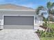 Modern home featuring a gray garage door, a brick driveway, and well-manicured landscaping at 8673 Seasalt Loop, Englewood, FL 34224