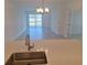 Bright living room features tile floors, large windows, and an elegant chandelier at 8673 Seasalt Loop, Englewood, FL 34224