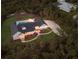 Aerial view showcasing the estate's layout, including the pool, outdoor kitchen, and expansive grounds surrounded by trees at 9144 Spring Valley Rd, Englewood, FL 34224