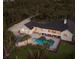 An aerial view reveals a pristine home with pool, outdoor kitchen, and lush landscape in a serene, private setting at 9144 Spring Valley Rd, Englewood, FL 34224