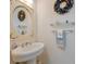 Powder room with a pedestal sink, decorative mirror, and coastal-themed wreath at 9144 Spring Valley Rd, Englewood, FL 34224