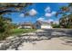Spacious home with a large driveway, wraparound porch, and a three-car garage, surrounded by trees at 9144 Spring Valley Rd, Englewood, FL 34224