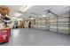 Spacious three car garage with painted floors, storage racks, an adjacent room and utility door at 9144 Spring Valley Rd, Englewood, FL 34224