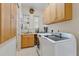 Bright laundry room features shaker cabinets, tile floors and modern washer and dryer at 9144 Spring Valley Rd, Englewood, FL 34224