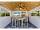 A shaded poolside bar area with a flat-screen television, granite countertop, and a grill at 9144 Spring Valley Rd, Englewood, FL 34224