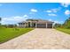 Paver driveway leads to a modern home with a three-car garage and lush green lawn at 9470 Wacker Ter, Port Charlotte, FL 33981