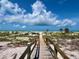 Walkway leading to a pristine white sand beach with clear turquoise water and lush dune vegetation under a bright blue sky at 9594 Doubloon Trl, Placida, FL 33946