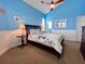 A bedroom features a ceiling fan and a view of a bathroom with a blue wall and white trim at 9594 Doubloon Trl, Placida, FL 33946