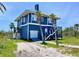 Coastal home featuring durable blue siding, a garage, an elevated deck, complemented by tropical palm trees at 9594 Doubloon Trl, Placida, FL 33946