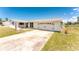 Single story home with an attached garage and a large driveway and lawn at 11 Oakland Hills Rd, Rotonda West, FL 33947