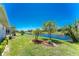 Lush backyard featuring vibrant landscaping and serene waterfront views on a sunny day at 1157 Rotonda Cir, Rotonda West, FL 33947