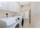 Bright laundry room features white washer and dryer, tiled floor, and white cabinets for storage at 1157 Rotonda Cir, Rotonda West, FL 33947