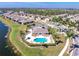 Aerial view of the community featuring a pool and clubhouse surrounded by lush landscaping and lake at 13392 Abercrombie Dr, Englewood, FL 34223
