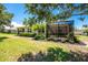 Exterior of home featuring screened lanai, landscaping, and expansive green lawn, perfect for outdoor enjoyment at 13392 Abercrombie Dr, Englewood, FL 34223