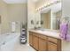 Well-lit bathroom featuring a soaking tub, wooden cabinets, light countertop, and decorative accents at 13392 Abercrombie Dr, Englewood, FL 34223