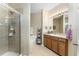 Bright bathroom with a glass-enclosed shower, soaking tub, wooden cabinets, and ample countertop space at 13392 Abercrombie Dr, Englewood, FL 34223