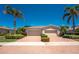 Charming home featuring a two-car garage, complemented by a well-manicured yard with symmetrical shrubbery and palm trees at 13392 Abercrombie Dr, Englewood, FL 34223
