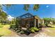 Backyard view of the screened lanai and the exterior of the home with lush landscaping and sunny skies at 13392 Abercrombie Dr, Englewood, FL 34223