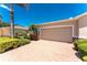Exterior view of the home and two car garage with brick driveway and maintained landscaping at 13392 Abercrombie Dr, Englewood, FL 34223
