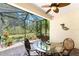 A screened lanai with seating area and brick flooring with a view of a wooded area at 13392 Abercrombie Dr, Englewood, FL 34223
