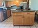 Well-appointed kitchen featuring an island, stainless steel appliances, wooden cabinets, and tile flooring at 13561 Darnell Ave, Port Charlotte, FL 33981