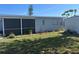 Exterior view of a home's back side, featuring a screened-in porch area and a storage shed in the yard at 13561 Darnell Ave, Port Charlotte, FL 33981