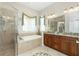 Elegant bathroom with a glass-enclosed shower, soaking tub, and dual vanities at 142 Savona Way, North Venice, FL 34275