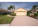 Charming home featuring a two-car garage with a brick paver driveway and mature palm trees at 142 Savona Way, North Venice, FL 34275