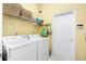 Functional laundry room features white washer and dryer, overhead shelving, and ample storage space, simplifying chores at 142 Savona Way, North Venice, FL 34275