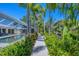 A serene pool area with lush tropical landscaping, including palms, vibrant flowers, and a charming wooden walkway at 142 Sunaire Ter, Nokomis, FL 34275