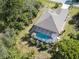 Aerial view of a house with a screened-in pool, surrounded by lush landscaping at 142 Yellow Pine Dr, Rotonda West, FL 33947
