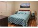 Comfortable bedroom with a patterned blue and white bedspread, mountain artwork, and wood floors at 142 Yellow Pine Dr, Rotonda West, FL 33947